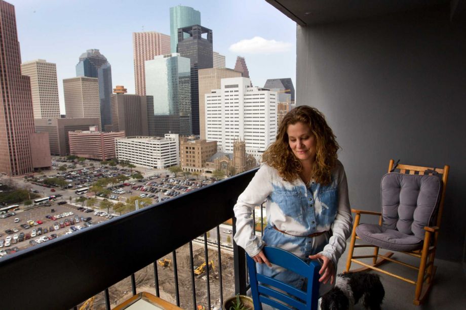Woman arranging patio furniture on the balcony of her downtown apartment